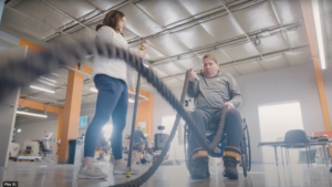 ALS patient in wheelchair performs physical therapy with ropes